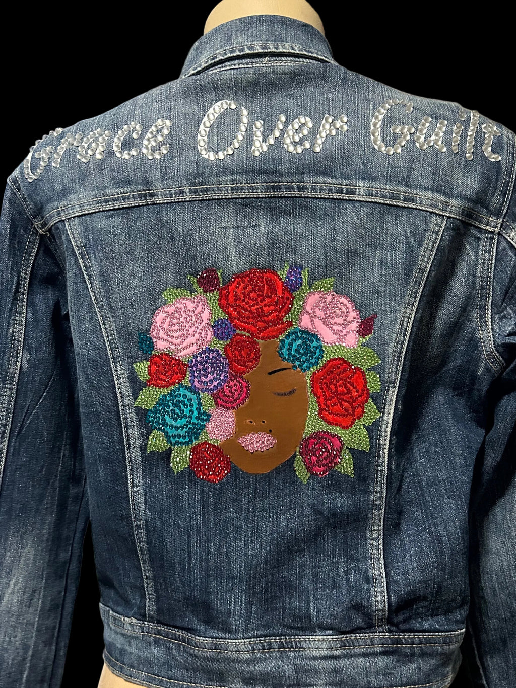 Denim jacket with floral design and 'Grace Over Guilt' text on a mannequin.